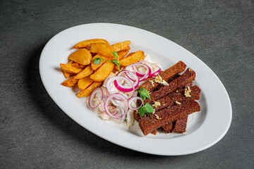 A plate filled with fried fish, crispy potatoes, and vibrant onion rings garnished with herbs