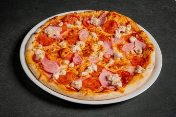A tempting pizza with pepperoni, ham, and melted cheese sits invitingly on a plate