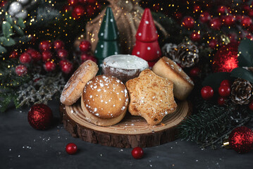 Different Spanish Christmas shortbreads or mantecados and polvorones on a wooden plate with christmas ornaments. Assortment of christmas sweets typical in Spain