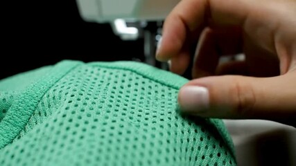 Close-up of a sewing machine needle stitching a textured green fabric with a clear focus on the detailed stitching and fabric texture