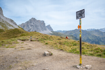 Wanderweg an der Landesgrenze mit historischem Schweiz-Schild vor beeindruckender Alpenkulisse