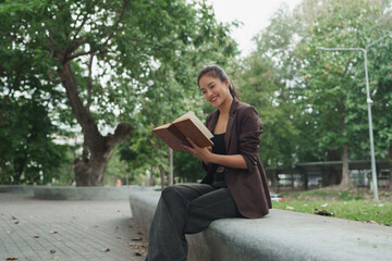 Fototapeta premium Young woman enjoying reading book for leisure outdoors