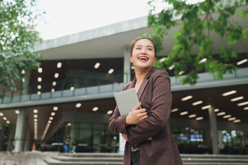 Young businesswoman smiling cheerful holding digital tablet outside modern building