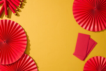 Red paper fans with red envelope decorated on yellow background. Minimal Chinese New Year background with copy space, ideal for Lunar New Year posters, product placement