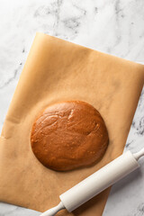 Preparation of gingerbread Christmas cookies. Raw dough and rolling pin on white marble table background, top view
