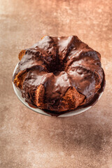 Chocolate marble bundt cake or zebra cake with chocolate glaze on brown table background isolated