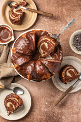 Chocolate marble bundt cake or zebra cake with chocolate glaze sliced on brown table background top view