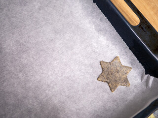 Star-shaped poppy seed cookie dough placed on baking parchment on a baking tray, prepared for Christmas baking. Traditional homemade festive cookies before baking.