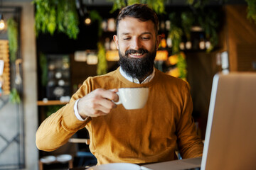 Portrait of business casual man sitting in cafeteria and enjoying his fresh coffee.