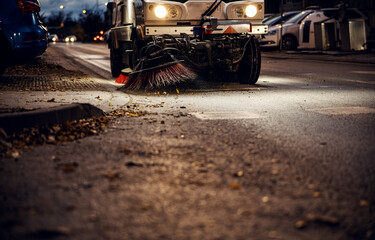Street sweeper cleaning urban road at night