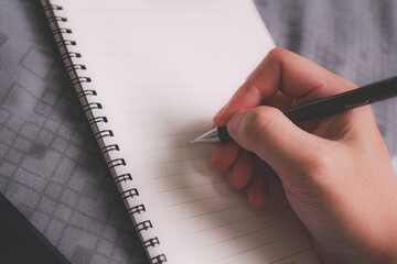 Close up of hand writing in notebook and blank planner page, concept of planning, goals and organization.