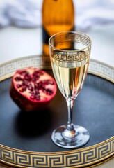 Elegant glass of white wine with pomegranate on a decorative tray