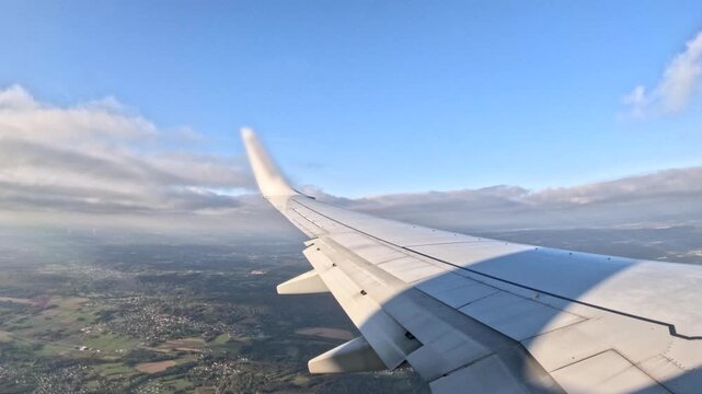 Airplane wing view above countryside during a sunny day flight