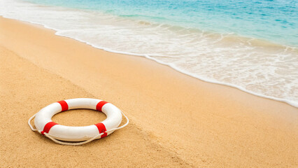 Obraz premium Lifebuoy placed on sandy beach near water with gentle waves and blue sky in bright daylight