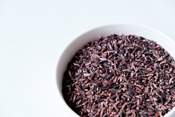 A bowl of black sticky rice grains isolated on white background