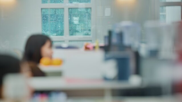 Cinematic blurred office interior with a soft-focused person working, while heavy snow falls outside a large window. Captures a tranquil winter atmosphere, ideal for background footage.