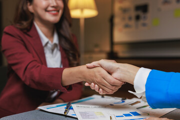 Businesswomen shaking hands completing deal over documents