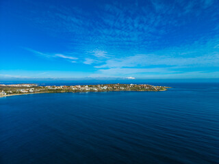 Majestic coastline view under a clear blue sky showcasing tranquil waters and scenic hills in the distance during a sunny day