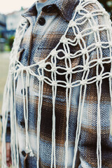 Unique textile art display featuring an intricately knotted design on a stylish flannel jacket in a serene outdoor setting during daylight hours