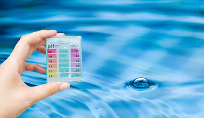 Water tester test kit in girl hand over blurred swimming pool water background, quality water testing test kit, pool maintenance and service business concept