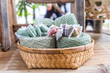 Natural color cotton thread roll in bamboo basket on bamboo bench, Thai organic cotton yarn roll with natural color dyed