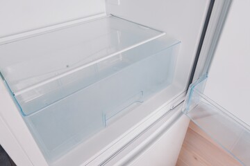 A Closer Look at the Interior of a Modern Refrigerator, Showcasing a Transparent Storage Drawer and Clear Shelving for Efficient Food Organization and Access