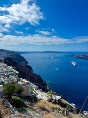 Stunning view of Santorini's cliffs and azure sea with boats sailing under a bright blue sky
