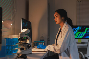 Female scientist researching genetic data at night in laboratory