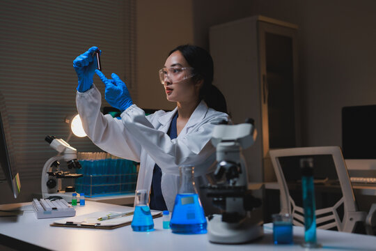 Female scientist analyzing sample in dark research laboratory - Powered by Adobe