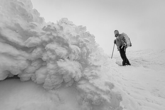 Hiker near ice formation in winter near Mount Washington