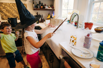 Kids play with fog at sink, girl in witch hat waves magic wand