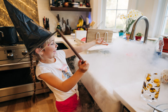 Girl pretending witch creating magic with dry ice smoke