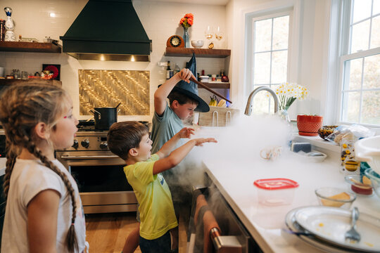 Kids create foggy magic with wand at kitchen sink on Halloween