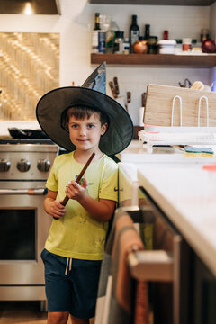 Boy playing wizard in kitchen holding magic wand