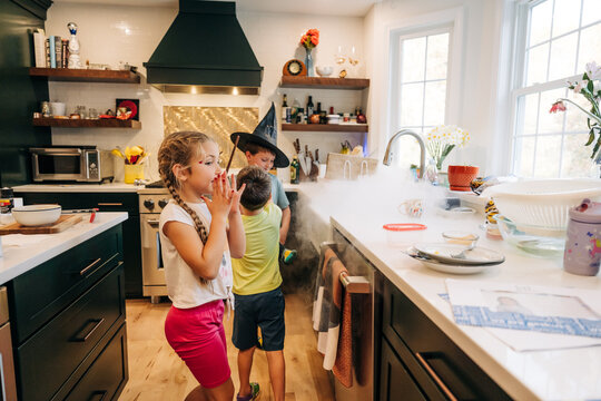 Children creating halloween dry ice magic experiment in kitchen