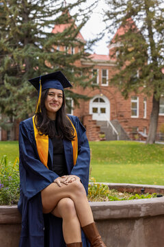Female graduate sitting outside architectural background