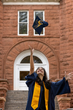 Female graduate tossing cap architectural background