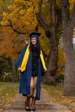 Female graduate walking under fall landscape vertical
