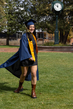 Female graduate walking outside clock background