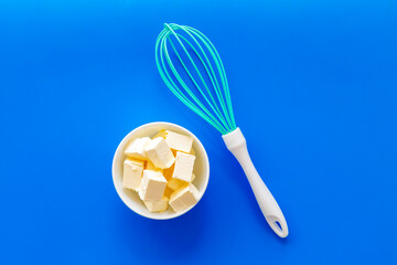 Butter sliced in white bowl with a whisk, top view