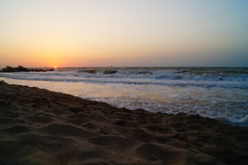 Sunrise on the seashore with waves on a warm summer morning