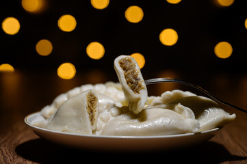 Christmas Eve dumplings stuffed with cabbage and mushrooms on a plate, with festive bokeh
