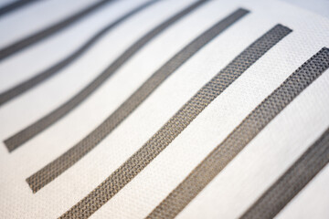 Macro of a white non-woven material with wavy grey stripes. An abstract, modern background with a shallow depth of field, creating perspective and movement.