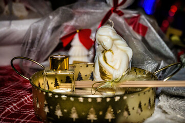 Festive gift tray with sculptural candle, aroma diffuser bottle, golden decor, red ribbons, cozy holiday mood, elegant still life, luxury home fragrance, Christmas celebration concept