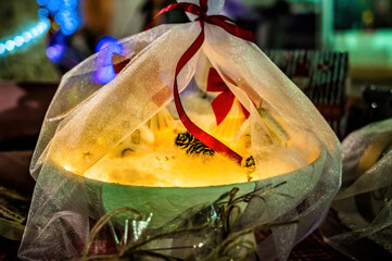 Festive glowing decoration wrapped in sheer fabric with red ribbon, warm light creating cozy holiday atmosphere, winter decor concept, magical illumination, handmade festive styling, romantic seasonal