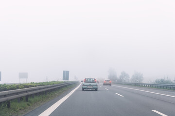 Driver POV of grey foggy misty rainy highway intercity road with low poor visibility on cold spring autumn morning. Seasonal bad rainy weather accident danger warning. car fog light