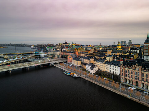 Aerial view of bridges connecting the vibrant city, with Gamla Stan's historic buildings contrasting against the dark water under a cloudy sky, Stockholm, Stockholm County, Sweden.
