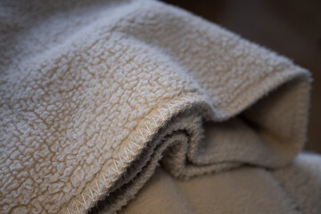 Macro shot of a soft, warm, cream-colored sherpa fleece fabric. The focus is on the textured material and stitched edge, creating a cozy and comfortable background. ©  Colorshadow