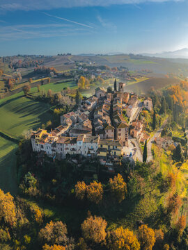 Aerial view of the ancient village atop a hill, bathed in the warm glow of the sun, contrasting with the cool shadows of the rolling hills, Morcella, Umbria, Italy.