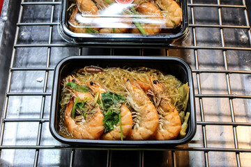 Authentic Thai street food — steaming shrimp with glass noodles in a takeout container, ready to eat on the go, perfect for travel or food delivery marketing.